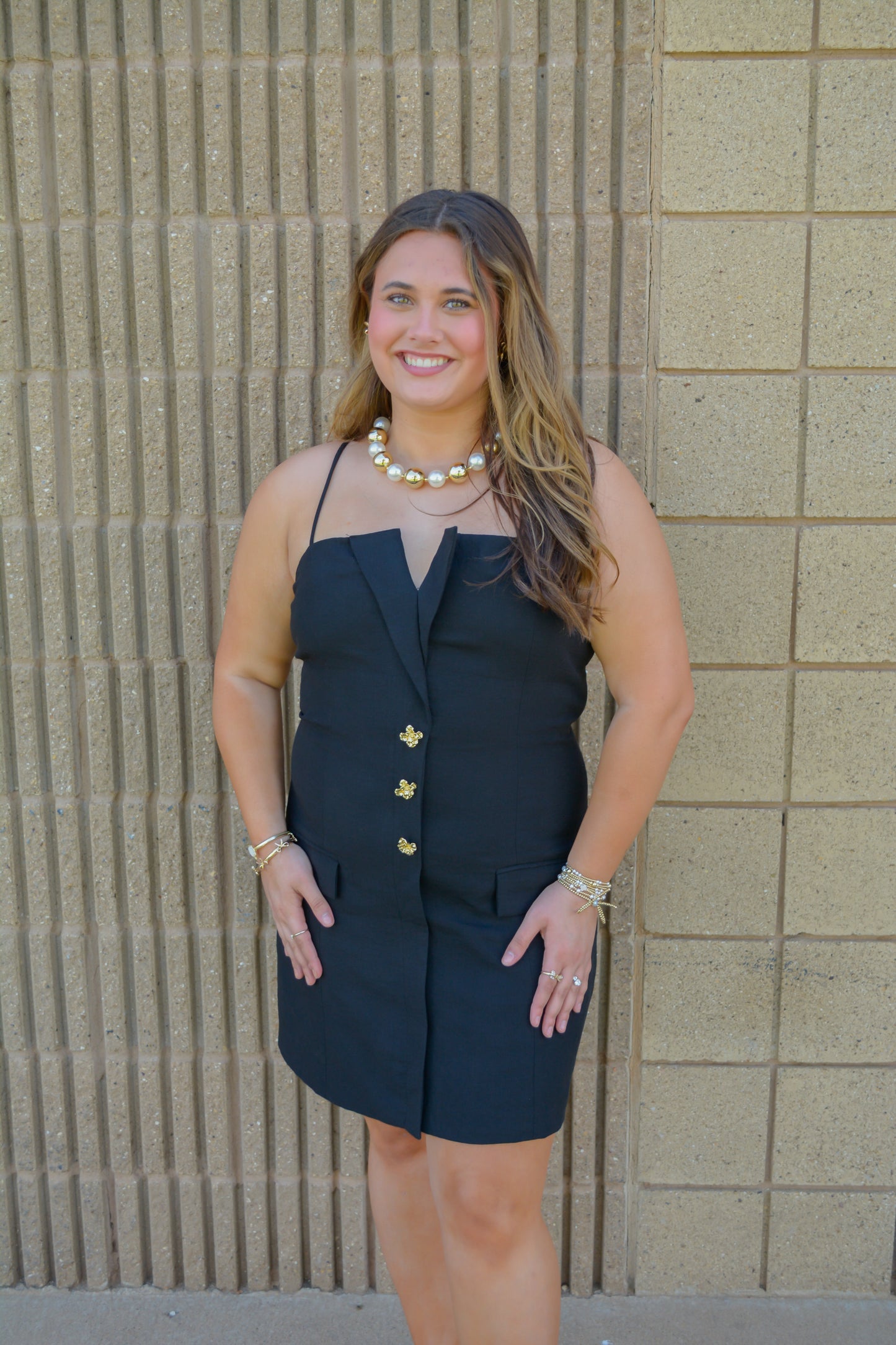 Strut & Bolt Midnight Elegance Button Mini Dress on a hanger, showcasing its dark fabric and stylish button details.
