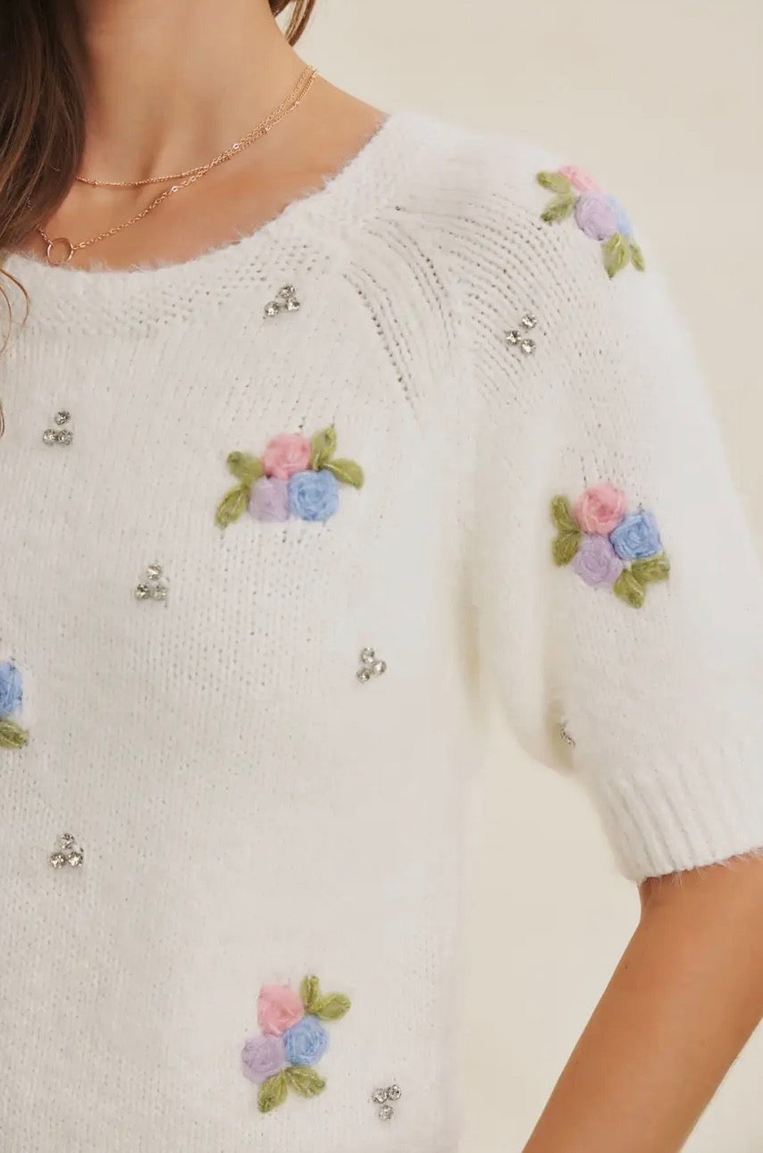 In February Bloom and Sparkle sweater, cozy knit with floral embellishments, shown on a model wearing it full view.