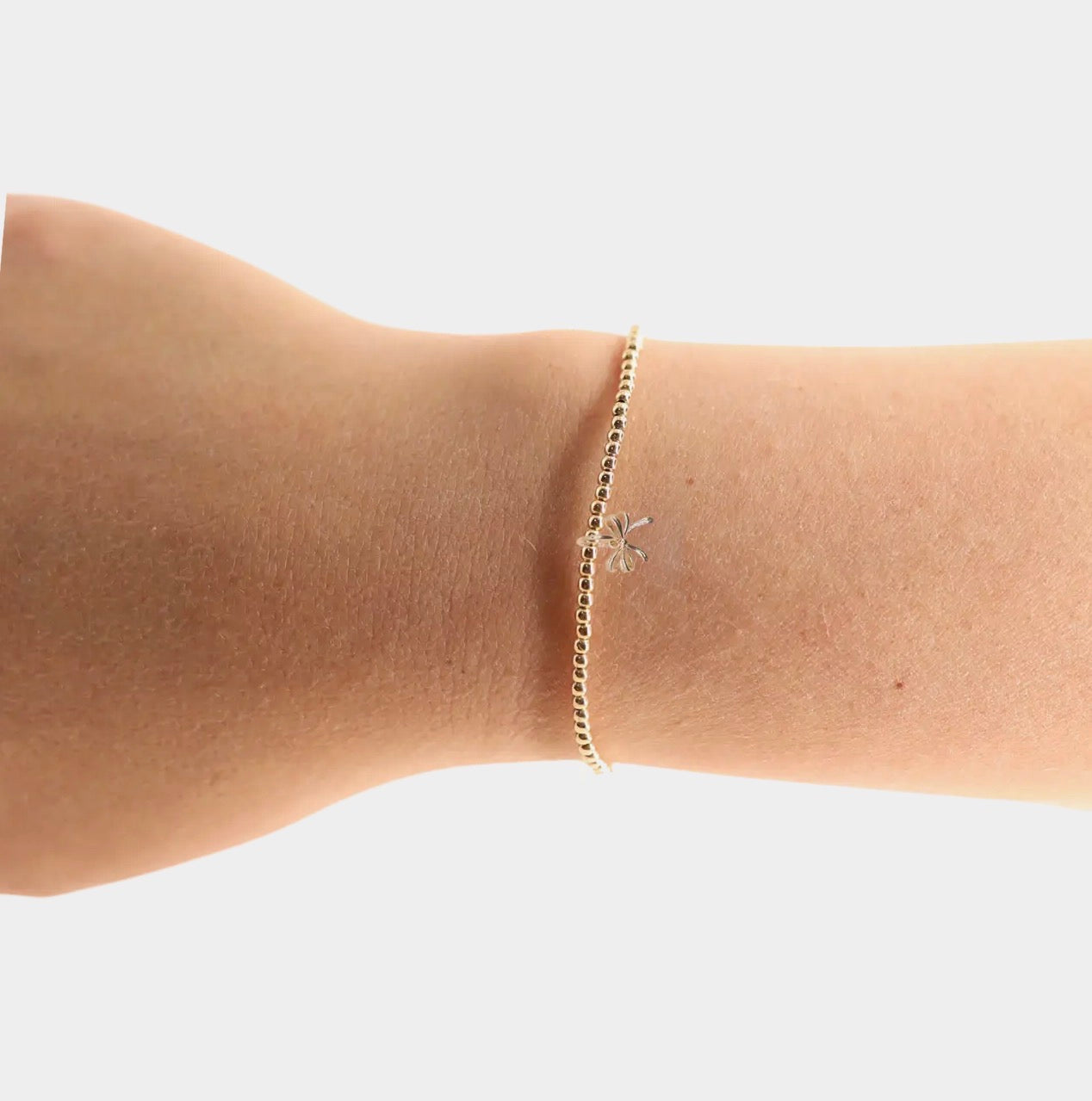 Gold bow charm bracelet with beaded blonde accents, stylish jewelry accessory from Beaded Blondes.