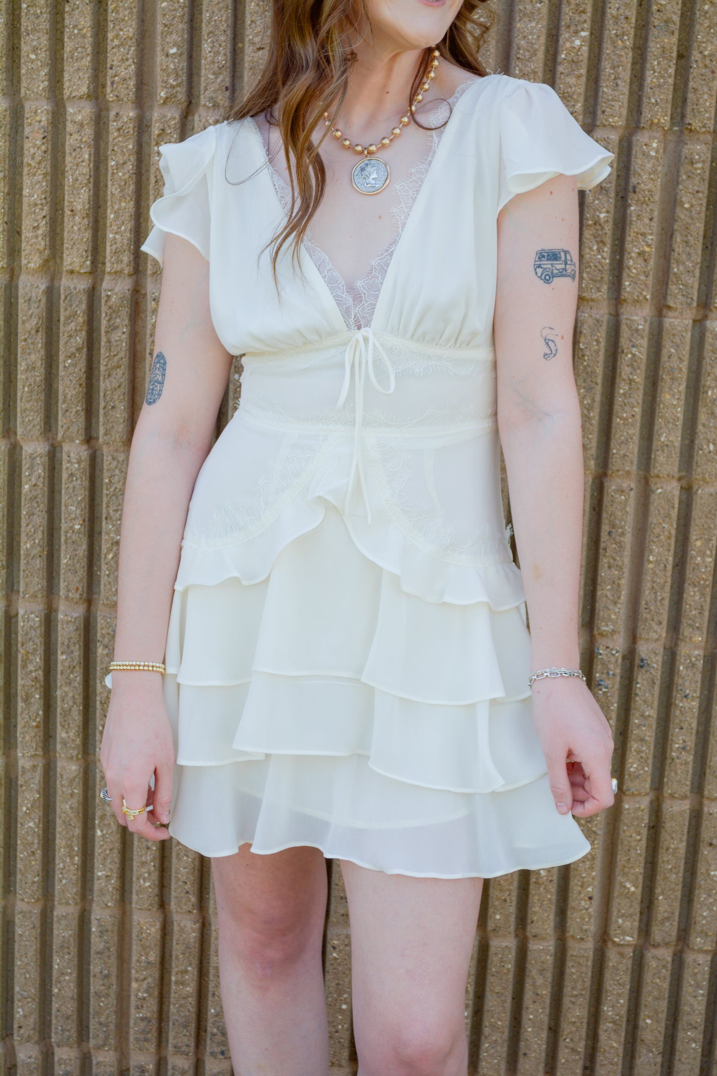 Ivory lace ruffle dress by Storia, featuring delicate lace fabric and layered ruffle details, perfect for elegant occasions.