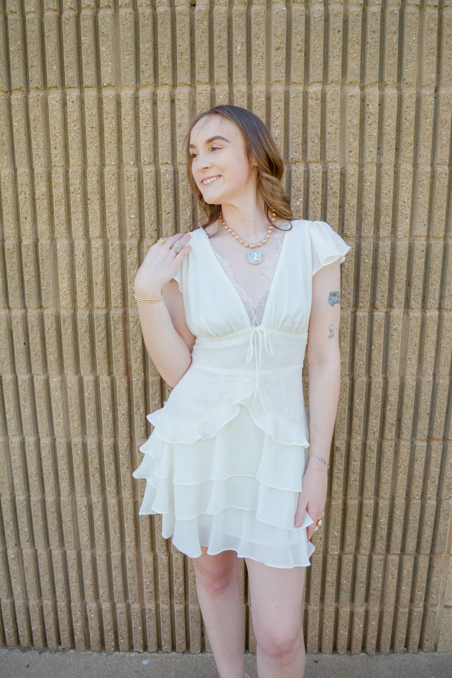 Ivory lace ruffle dress by Storia featuring delicate lace fabric and layered ruffle details on the skirt.