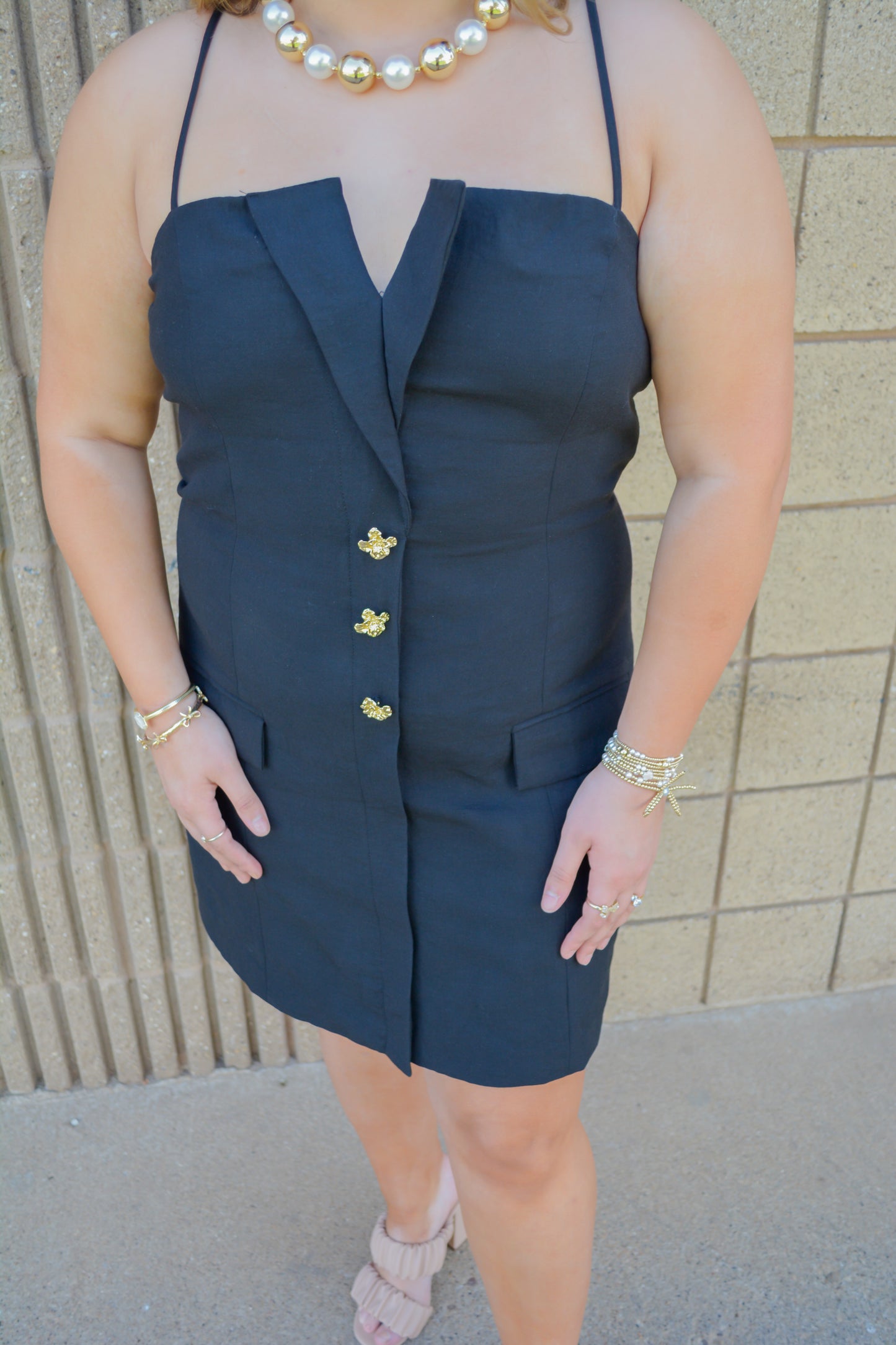 Strut & Bolt Midnight Elegance Button Mini Dress displayed on a hanger, showcasing the stylish black dress with button details.