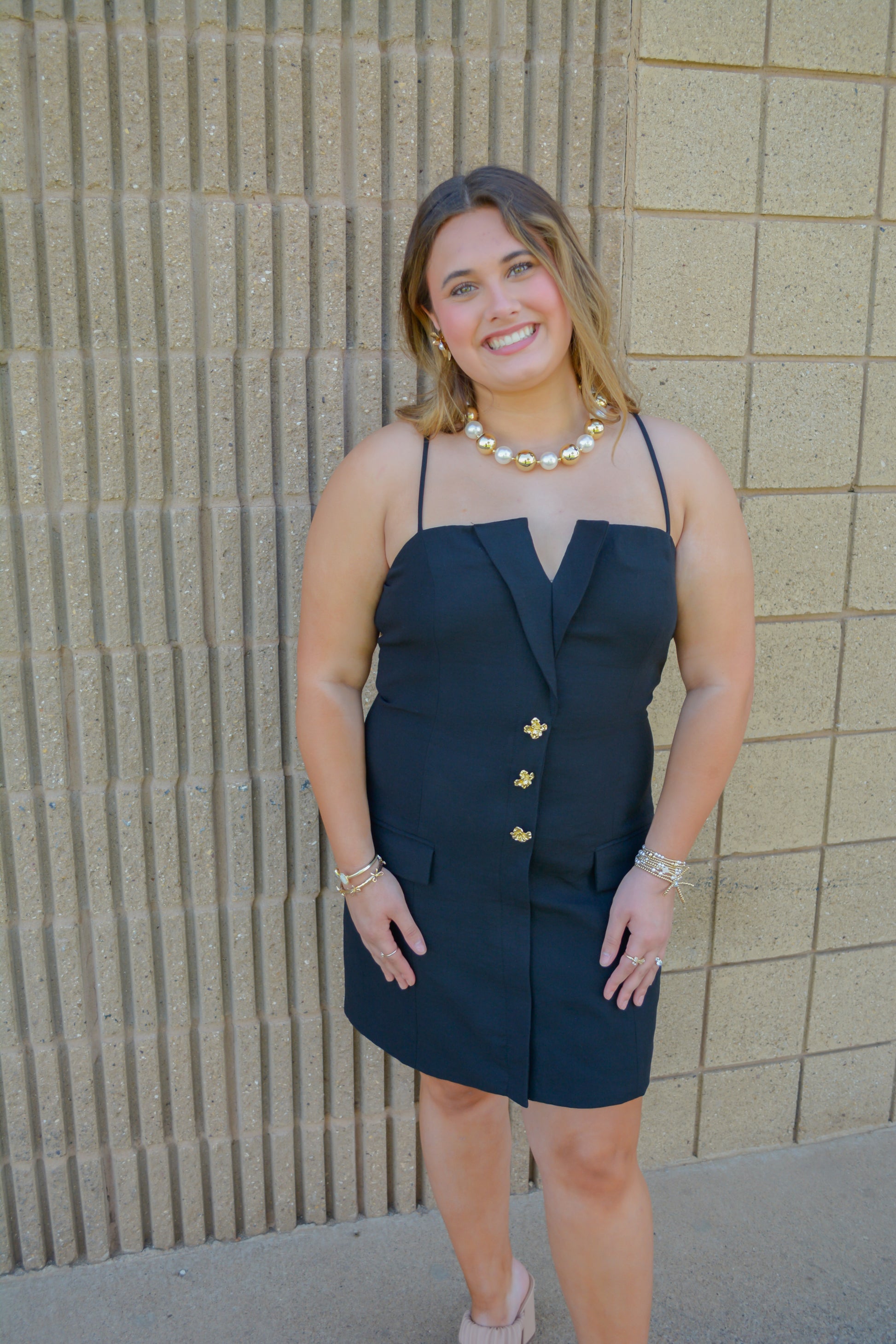 Strut & Bolt Midnight Elegance Button Mini Dress displayed on a hanger with a close-up of the black fabric and button details.