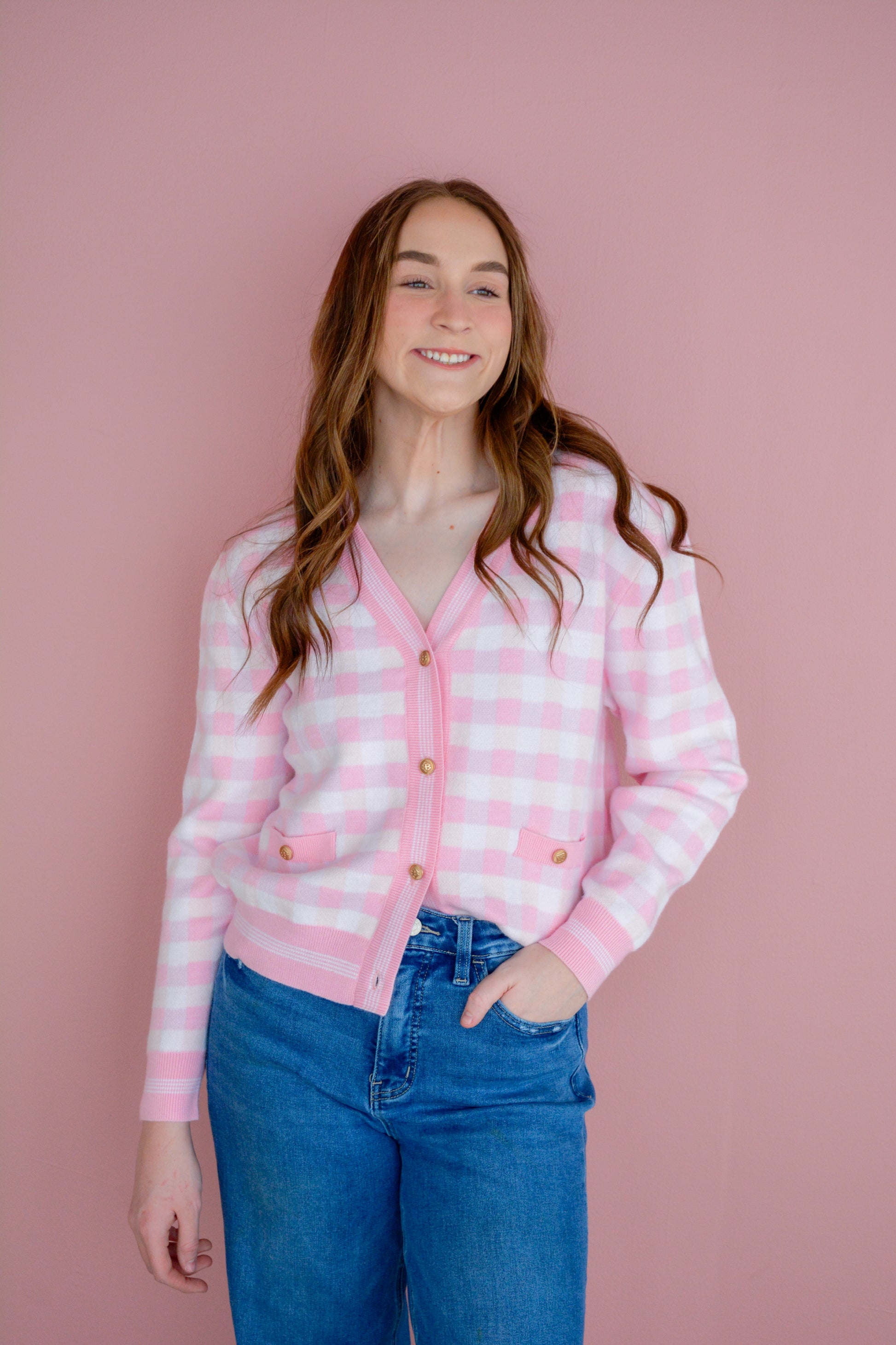 Pink gingham cardigan by Brianna Cannon, lightweight knit with button front and long sleeves, styled on a model.