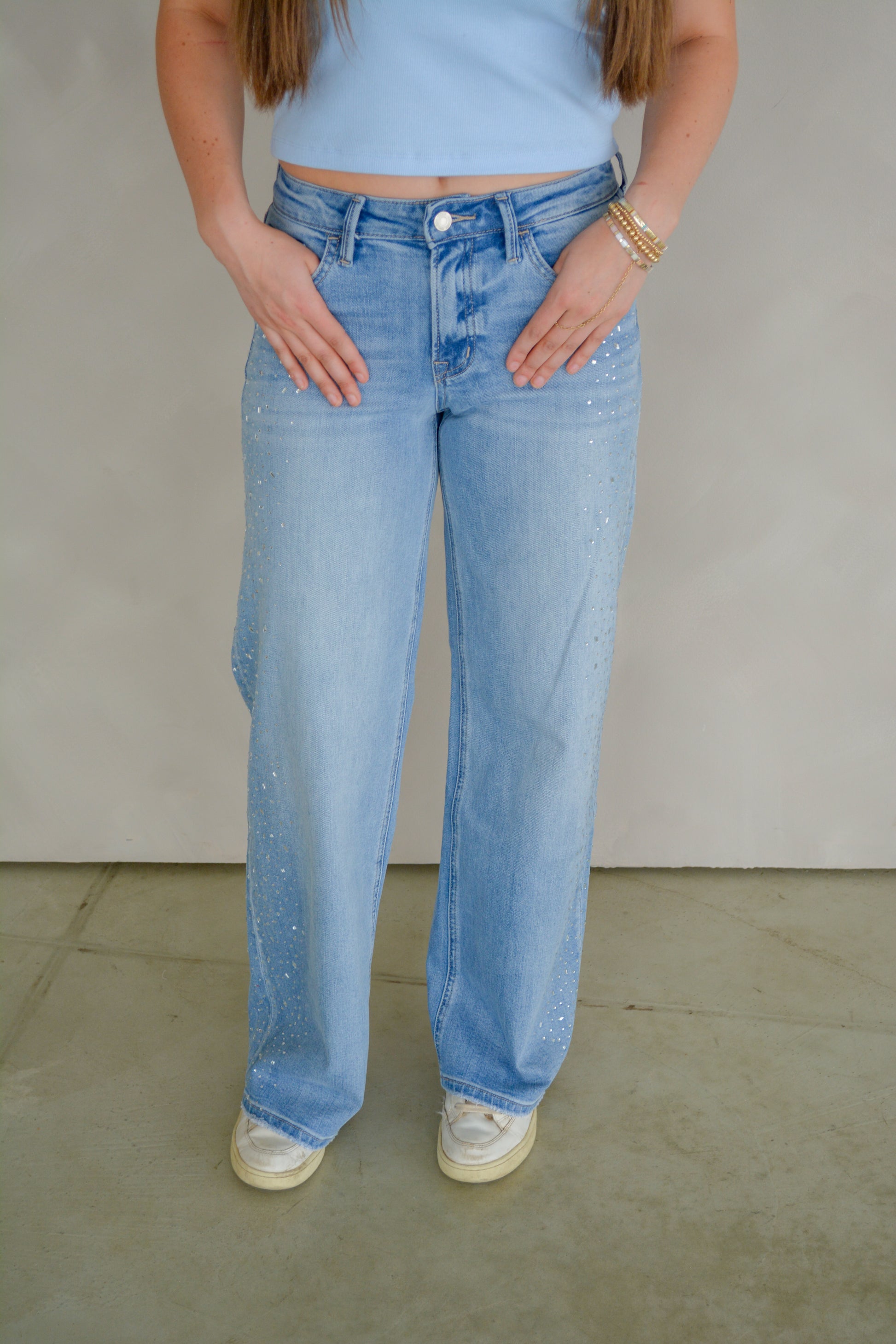 Vervet Glam wide-legged jeans hanging on a rack, showcasing their high-waisted design and relaxed fit.