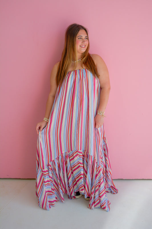 TCEC Summer Skies Maxi Dress with flowing fabric and floral pattern, displayed on a hanger outdoors.