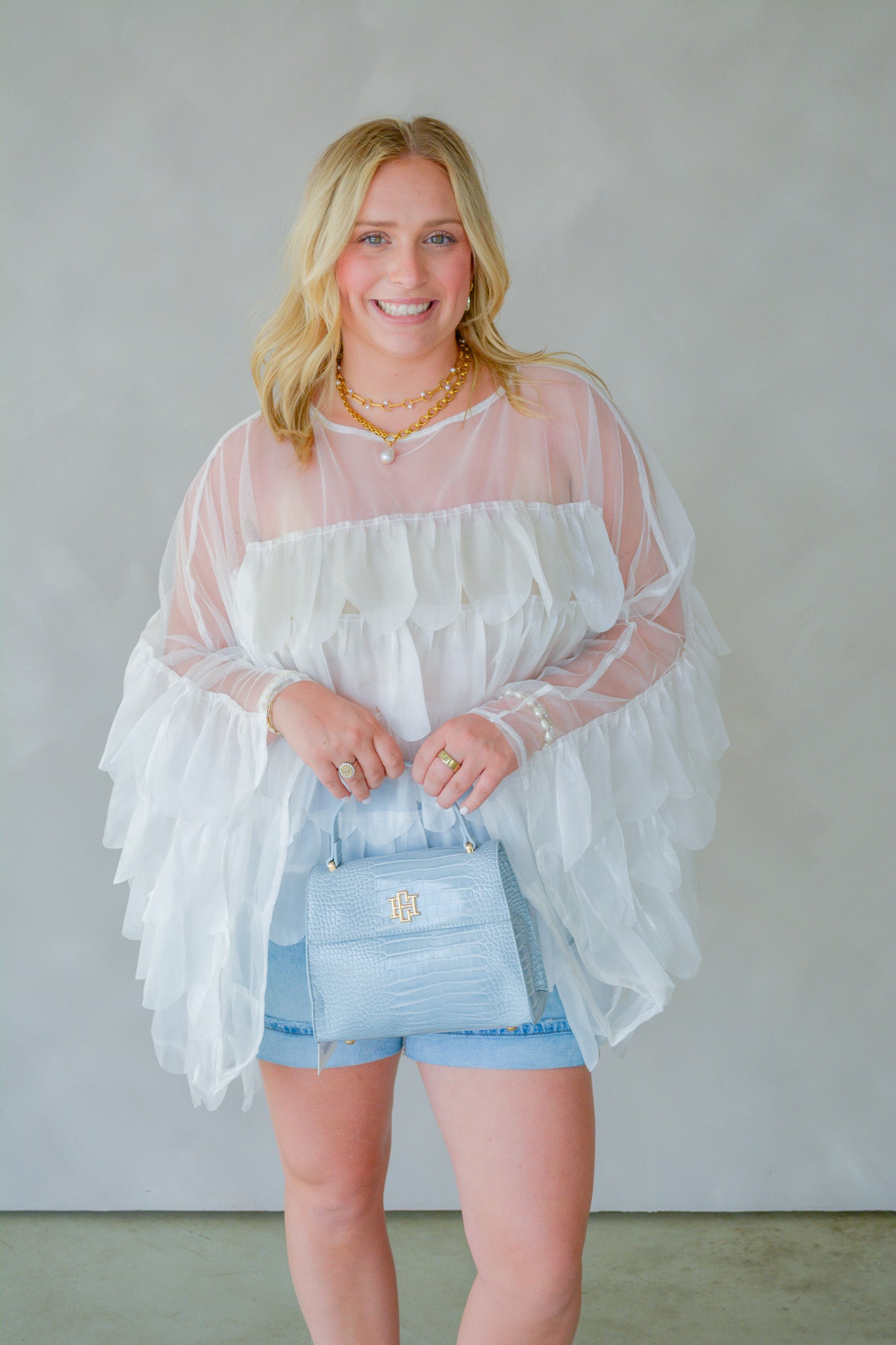 INA Pure Romance Ruffle Top displayed on a hanger, featuring a soft fabric with ruffled neckline and short sleeves.