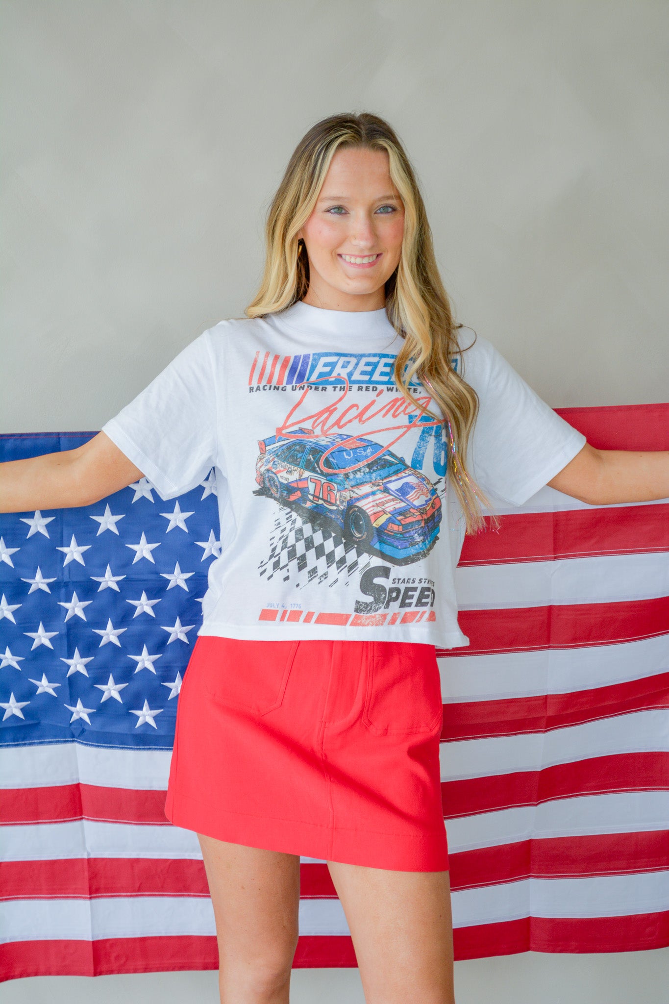Stars, stripes, and speed design cropped T-shirt by Chaudoin Creations displayed on a hanger.