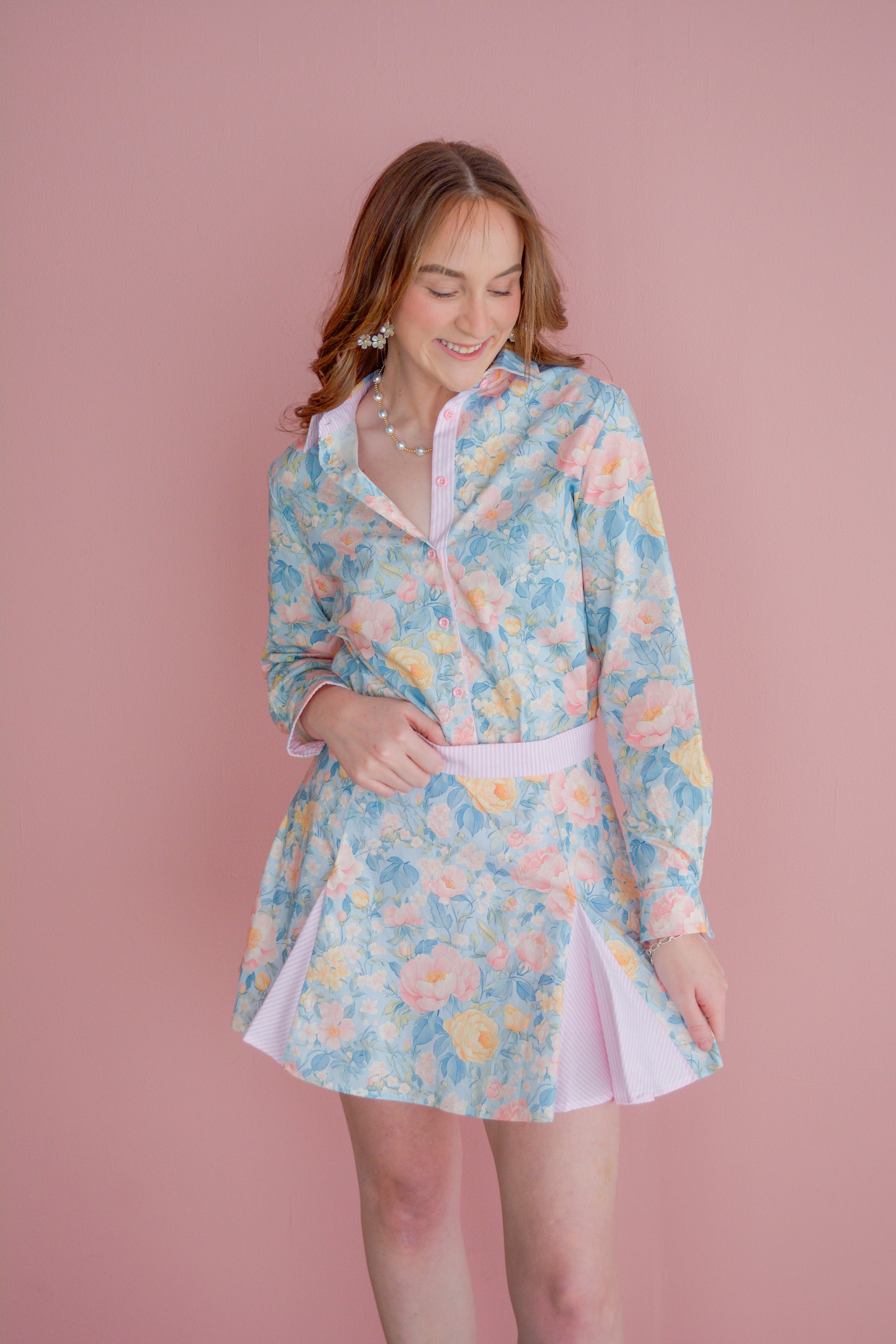 Brianna Cannon preppy floral pleated skirt with a high waist and vibrant flower pattern, styled with a white blouse.