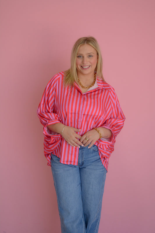 GLAM Sunset Drift Blouse in soft fabric with a flowing design, showcased on a hanger with a subtle sunset background.