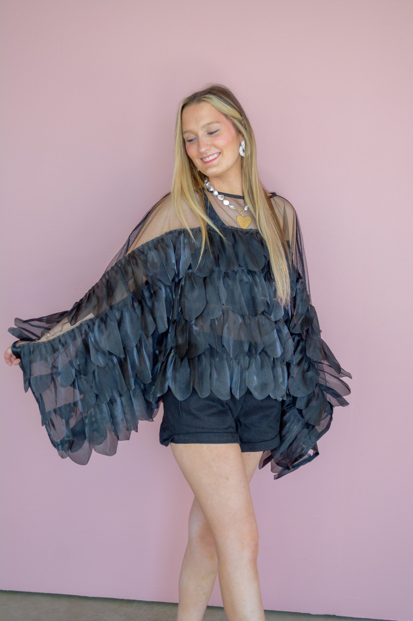INA Midnight Romance Ruffle Top featuring delicate ruffles and dark fabric, displayed on a hanger against a neutral background.