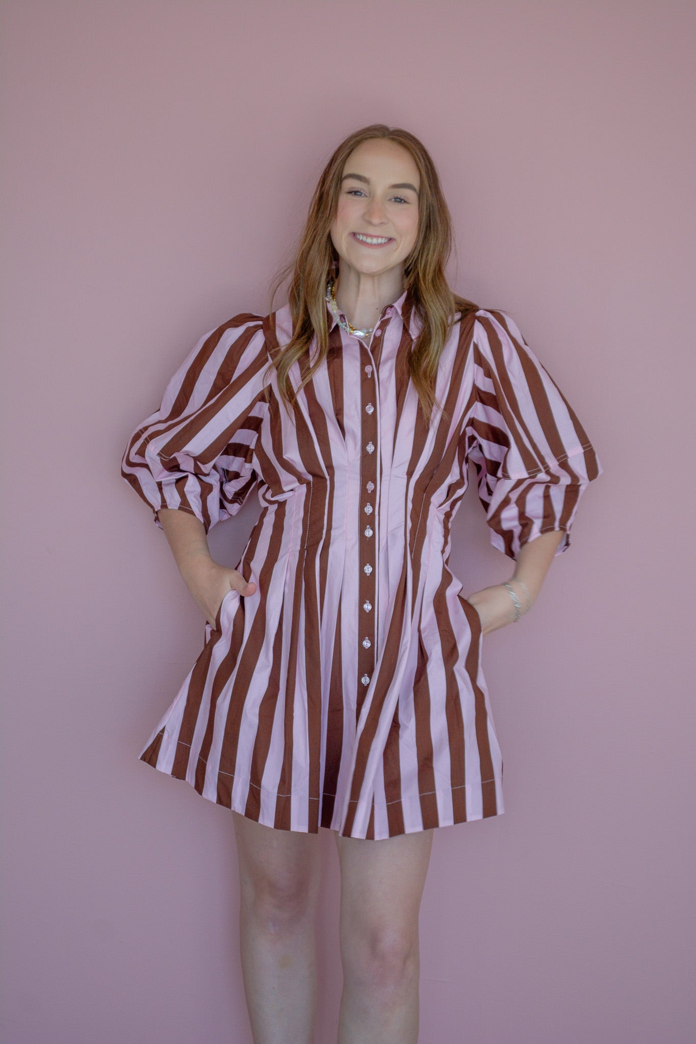 Strawberry Mocha Dress by Peach Love California displayed on a hanger with floral background.