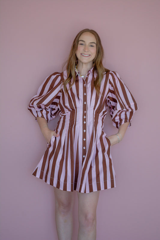 Strawberry Mocha Dress by Peach Love California displayed on a hanger with floral background.