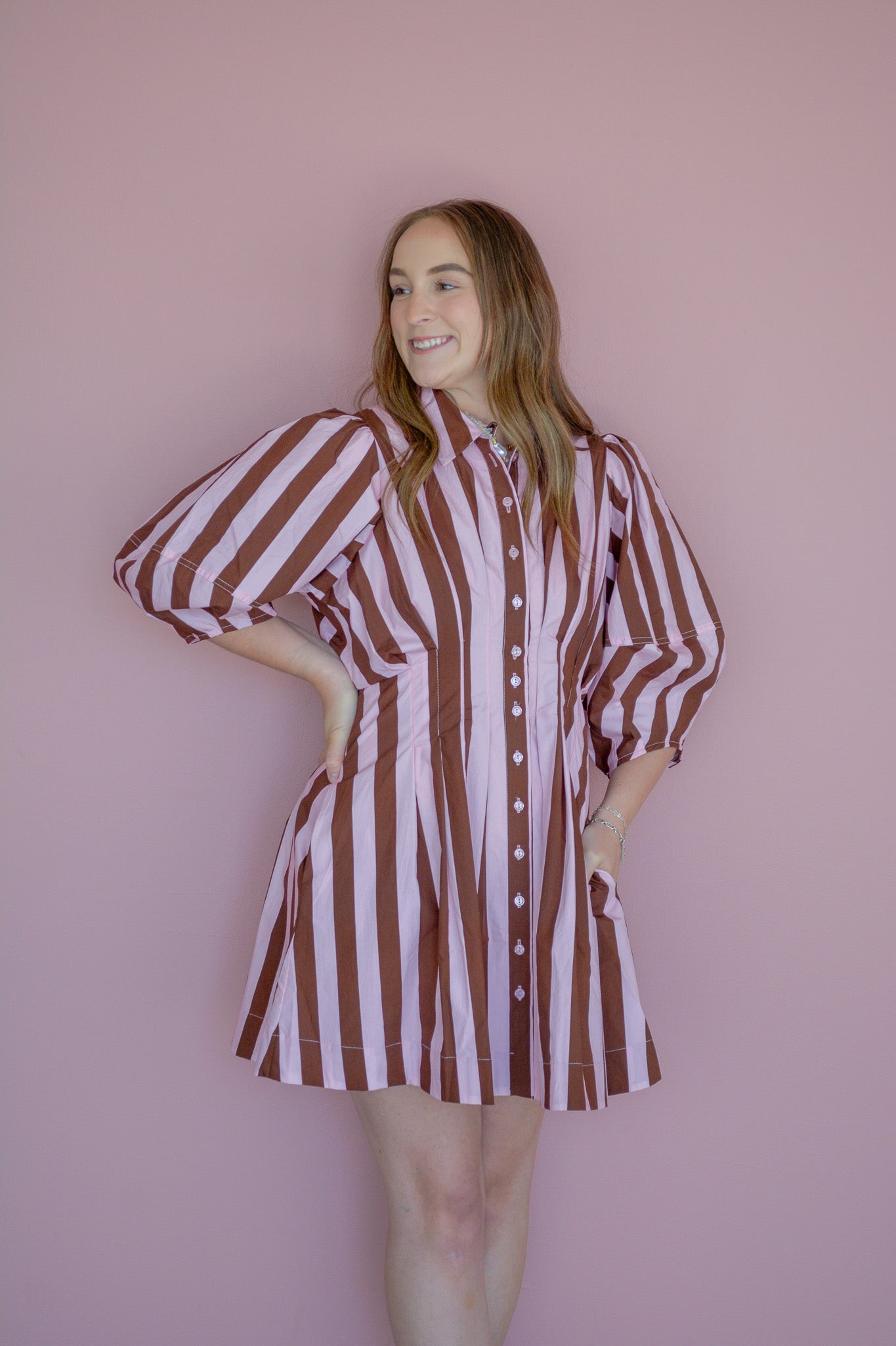 Strawberry Mocha Dress by Peach Love California displayed on a hanger, showcasing its stylish design and vibrant color.