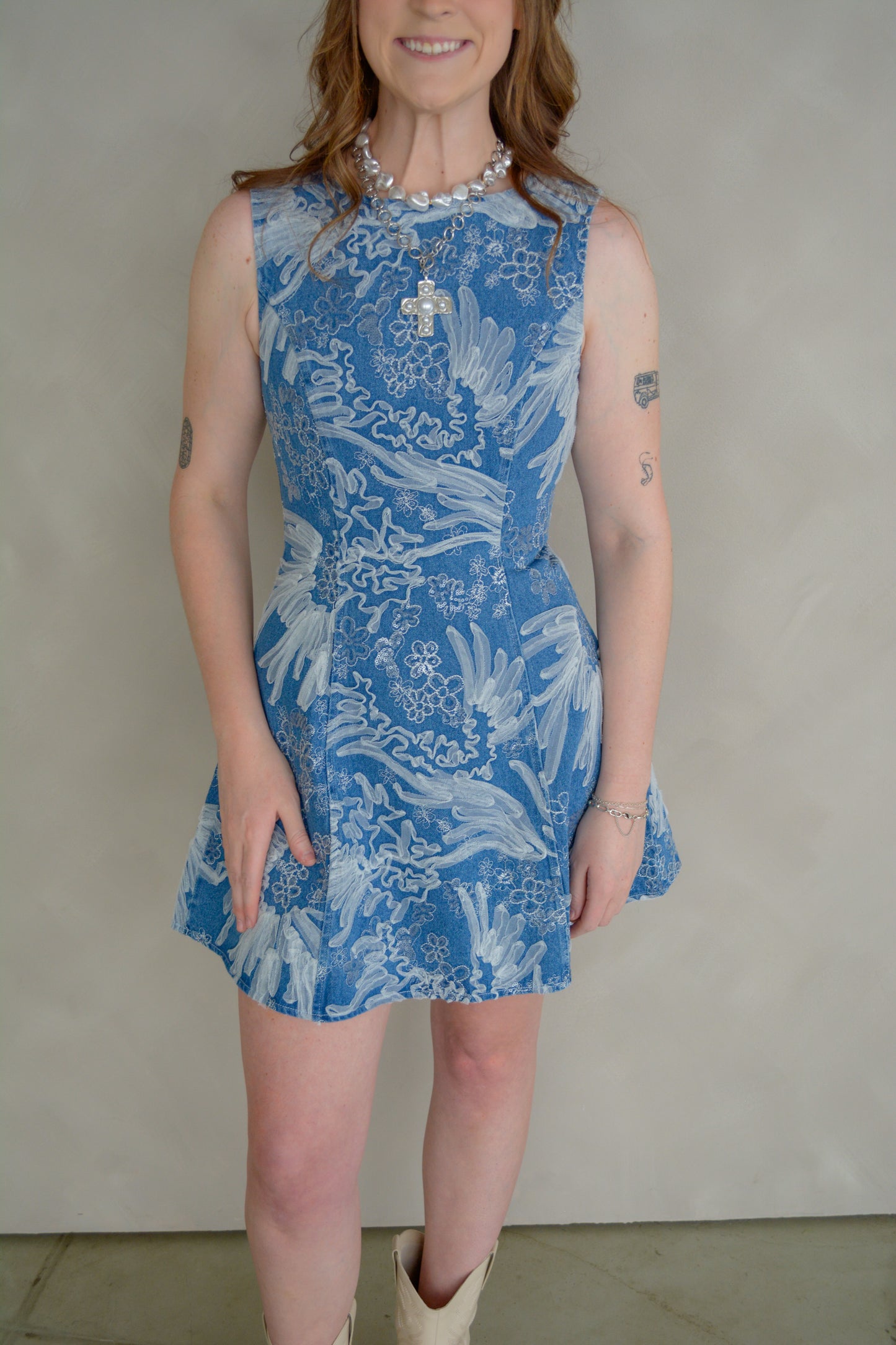 Baby Pink Anneliese embroidered denim mini dress displayed on a hanger, showcasing detailed embroidery and classic denim style.