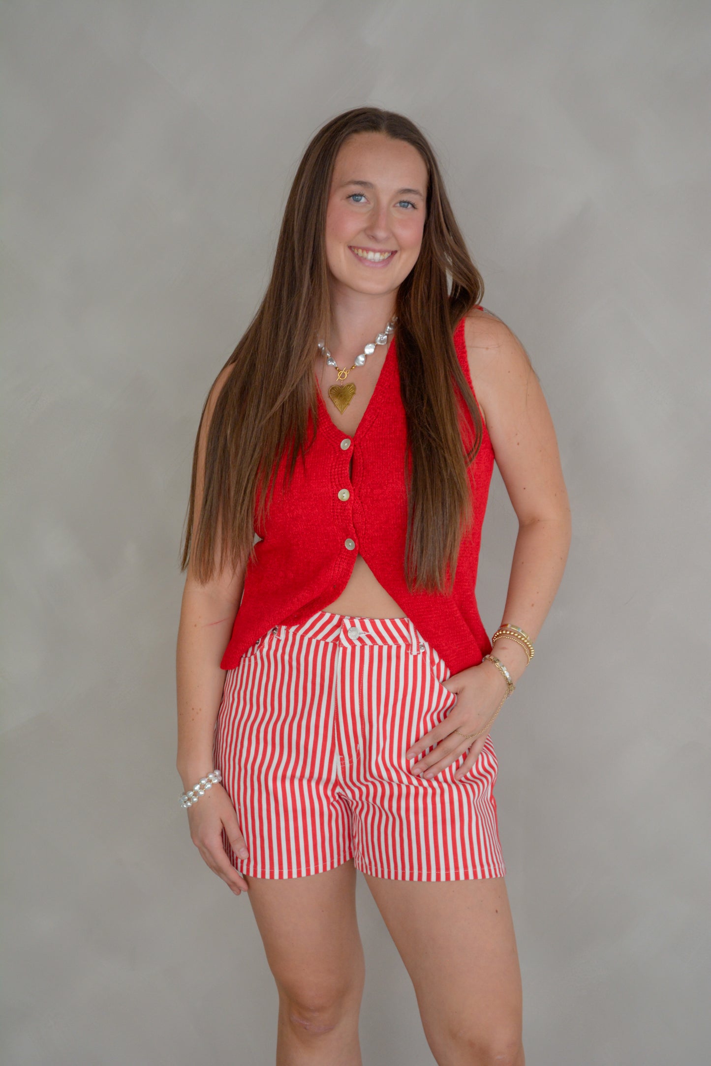 Red She+Sky The It Girl Sweater Vest displayed on a hanger, showcasing its stylish knit design and vibrant color.