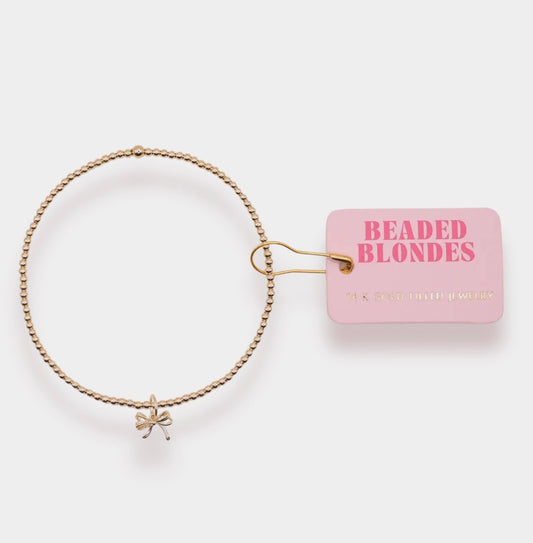 Gold bow charm bracelet by Beaded Blondes with beaded strands and delicate gold accents on a white background.