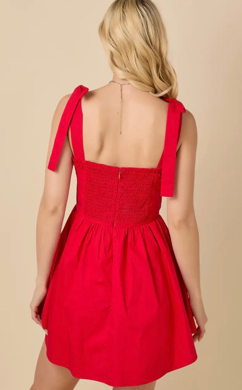 Red ruched mini dress by Baby Pink displayed on a hanger with a fitted, stylish design perfect for casual or party wear.